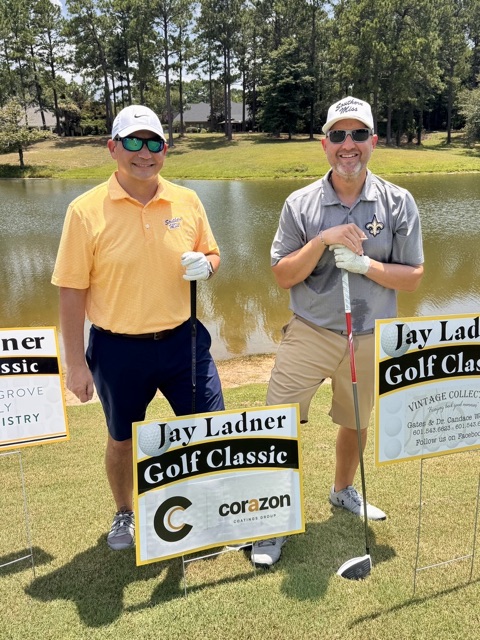 Kyle and Dane at the Jay Ladner Golf Classic behind a sponsor sign carrying the Corazon Coatings Group logo